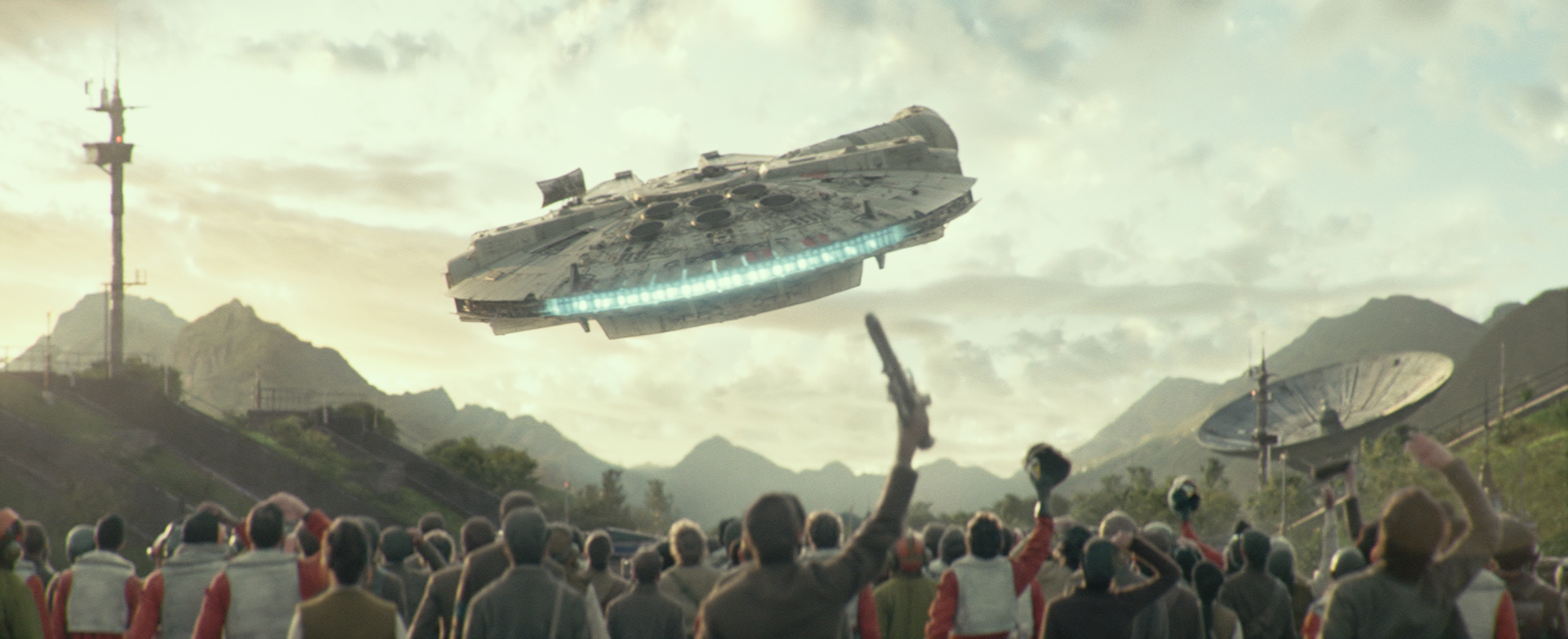 A film still from Star Wars: The Rise of Skywalker. A Resistance crowd cheers as the Millennium Falcon flies away.