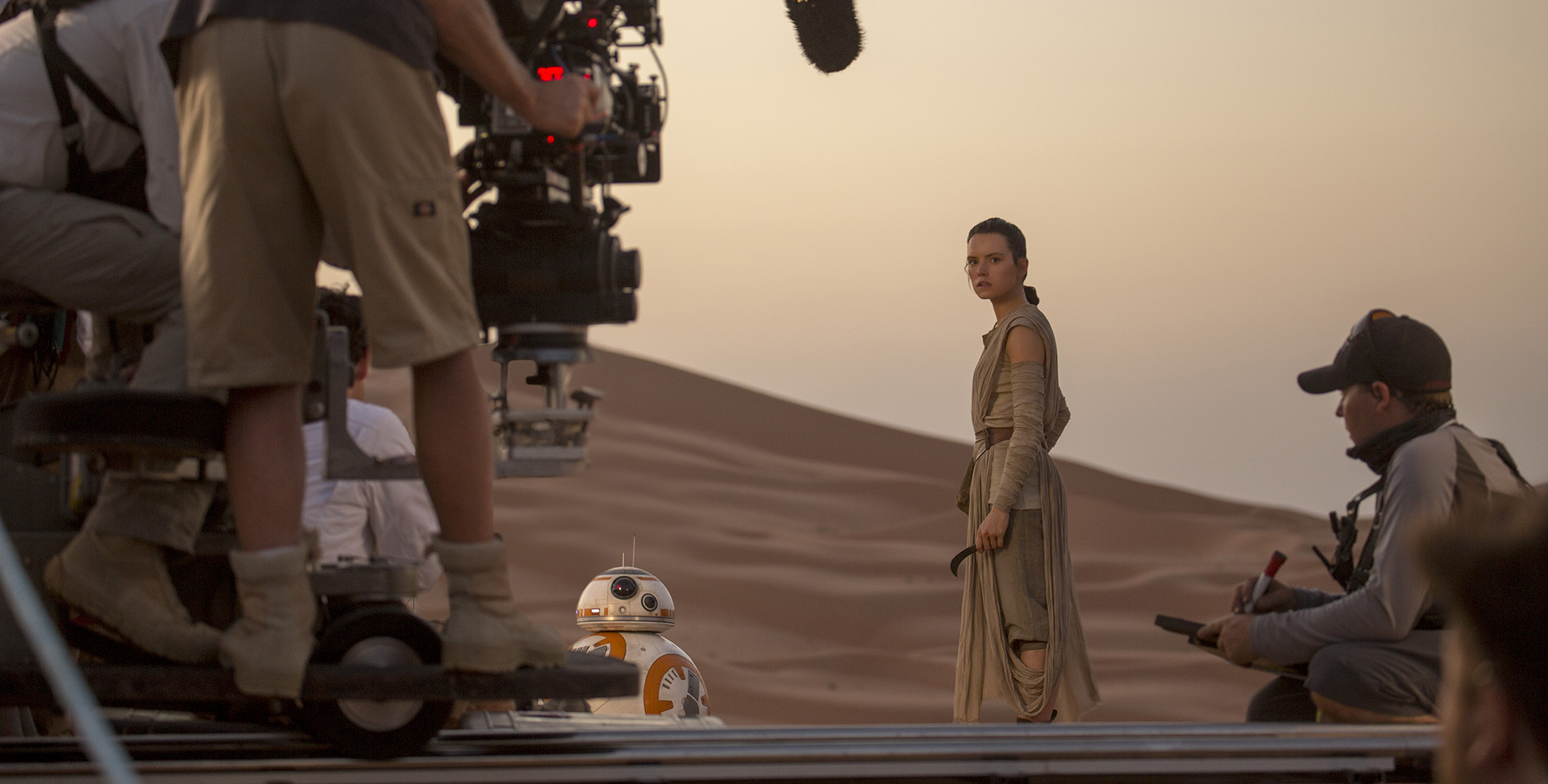 A behind-the-scenes shot of the filming of Star Wars: The Rise of Skywalker featuring a few crew members, Rey and BB-8.