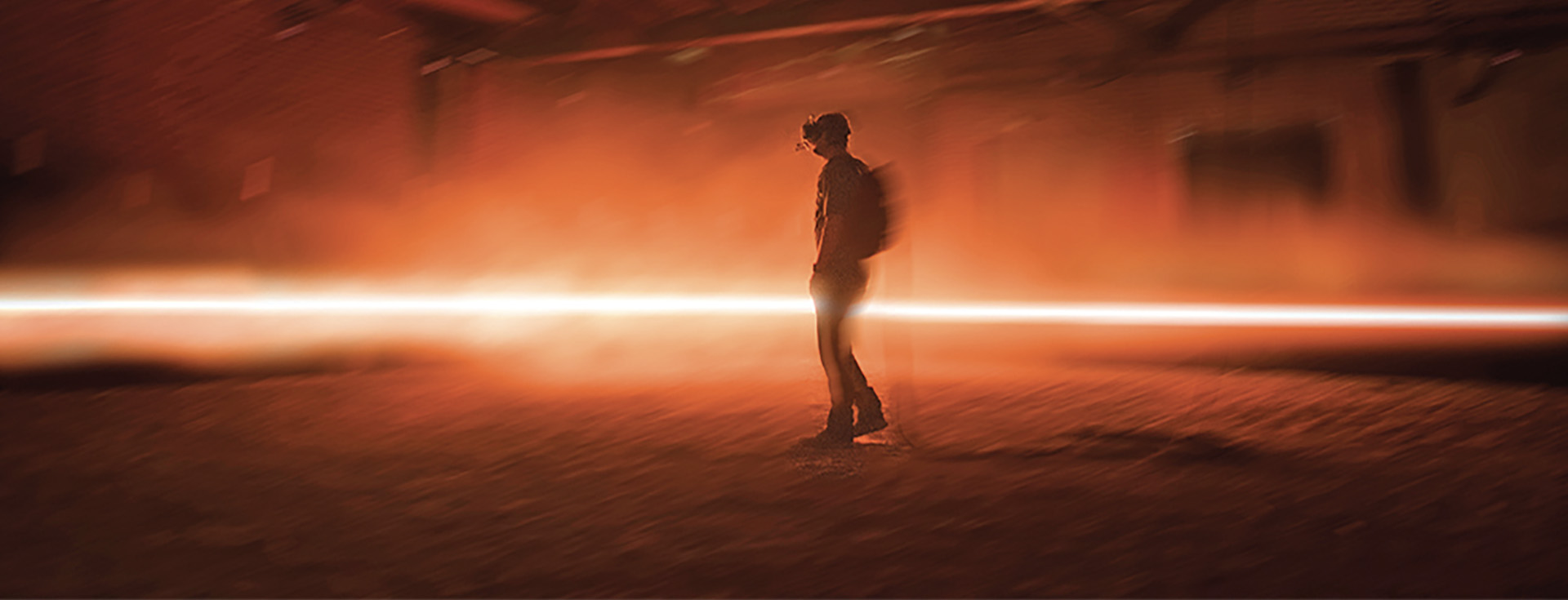 An image of a person wearing a virtual reality headset, walking through an orange glowing virtual reality environment.