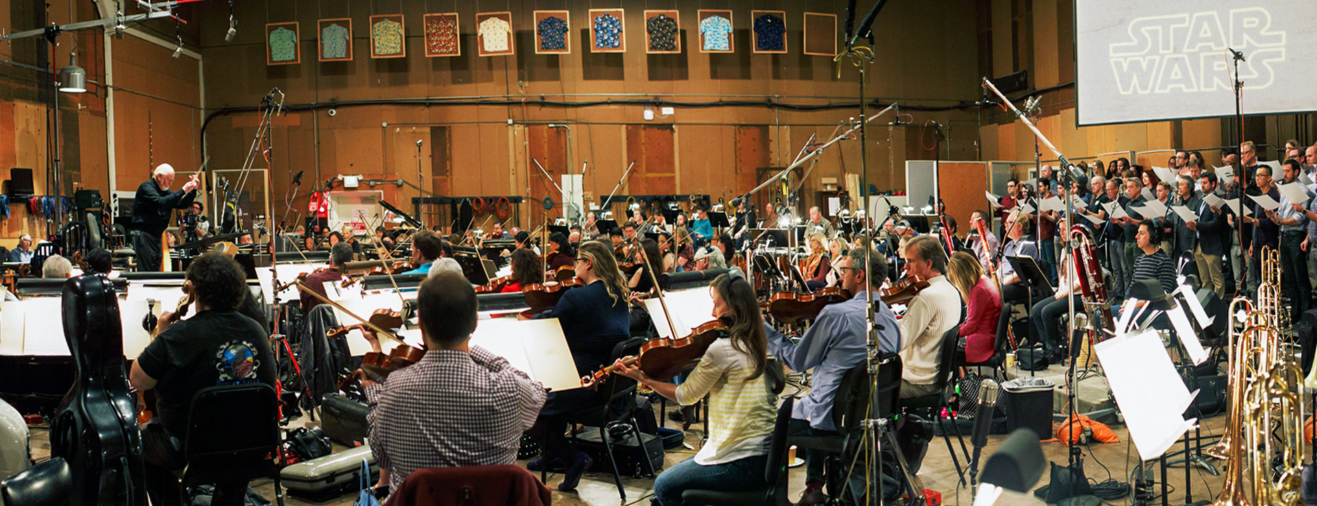 A wide view of John Williams conducting a large orchestra.