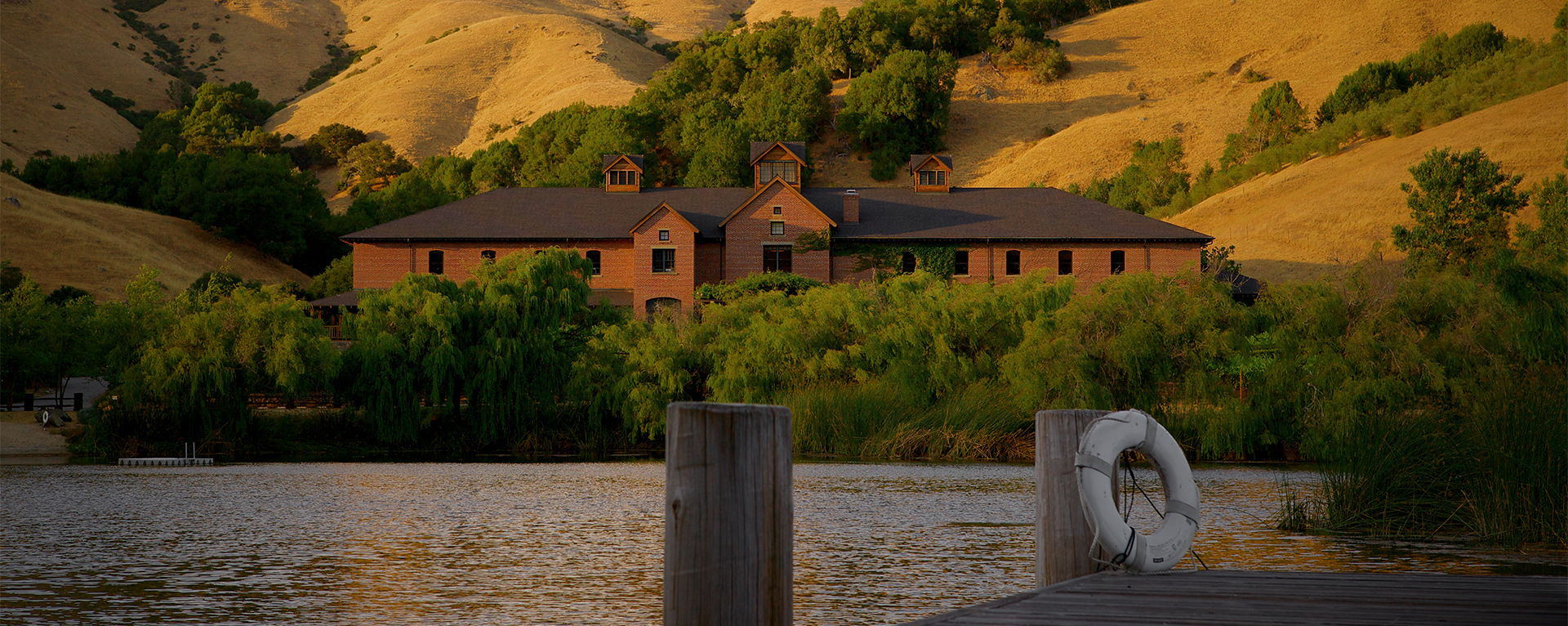 A view of the Tech Building at Skywalker Ranch in Nicasio, California. There is a pond in the foreground and hills behind the building.