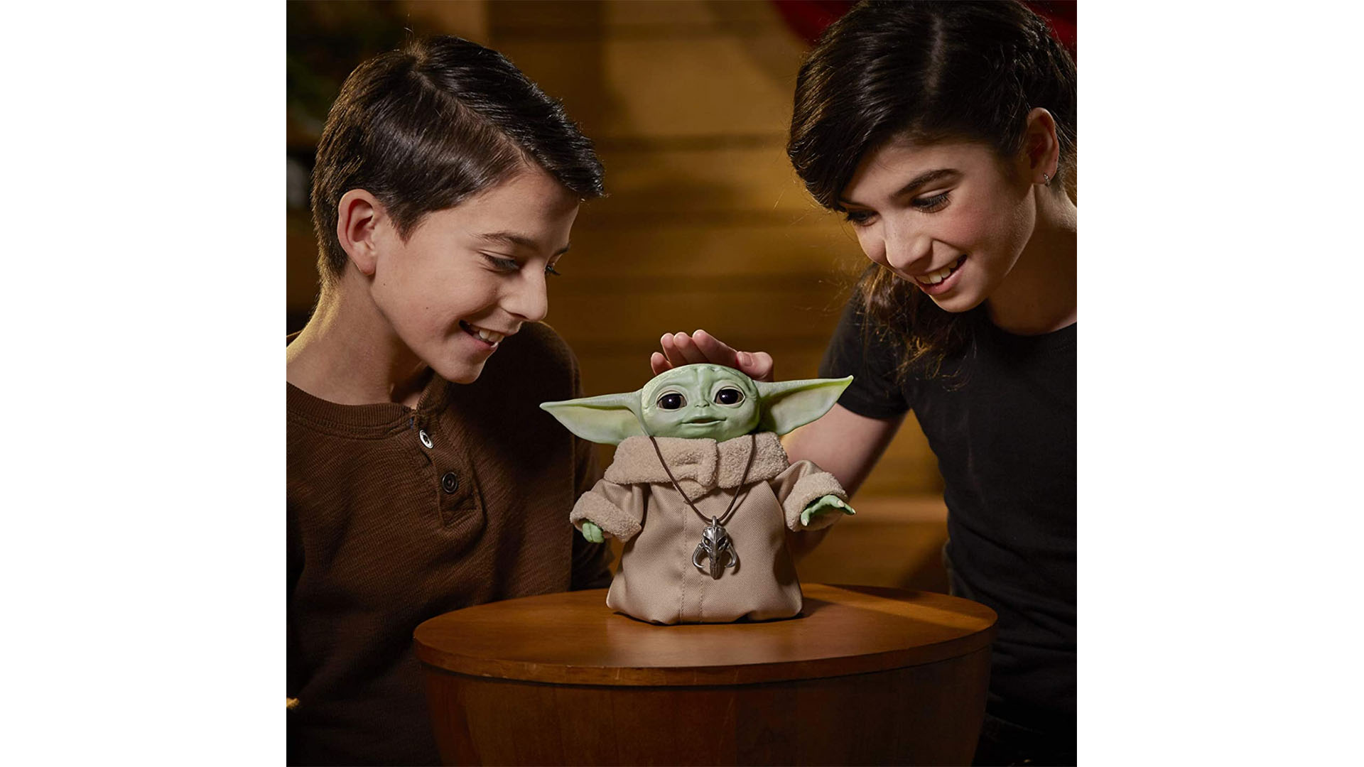 Two children play with a life-sized animatronic toy of The Child from Star Wars: The Mandalorian.