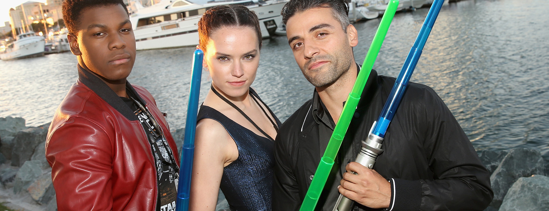 John Boyega, Daisy Ridley and Oscar Isaac pose with plastic lightsabers.