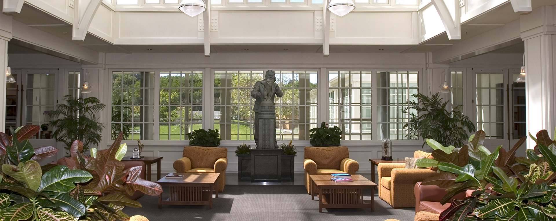 The sunlit public lobby of Lucasfilm's Headquarters at the Letterman Digital Arts Center in the Presidio of San Francisco, California. The lobby has two large coffee tables surrounded by armchairs and green leafy plants