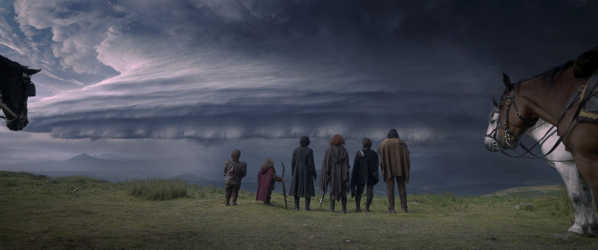 Stopping atop a mountain overlook to view what lies ahead, a dark, brewing storm is swirling over the landscape below